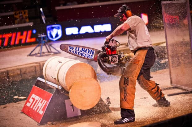 A lumberjack is cutting large logs with a chainsaw at a competition event, 2K Desktop Wallpaper