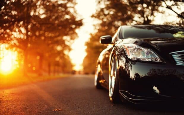 A sleek Infiniti G37 is parked on a road with warm sunset lighting and autumn trees, 2K Desktop Wallpaper