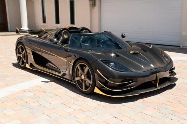 A sleek black Koenigsegg with gold accents parked outside a modern house, HD Desktop Wallpaper