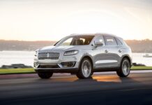 A silver Lincoln car is driving along the waterfront road at sunset in this Lincoln car wallpaper, 4K Desktop Wallpaper