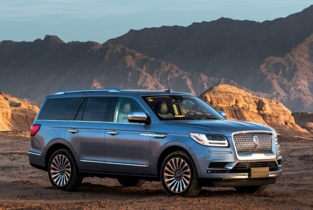 A blue Lincoln car is shown with mountains in the background during sunset, HD Desktop Wallpaper