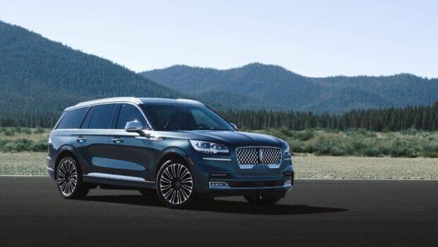 A sleek Lincoln car is parked on a blacktop road with green hills in the background, 4K Desktop Wallpaper