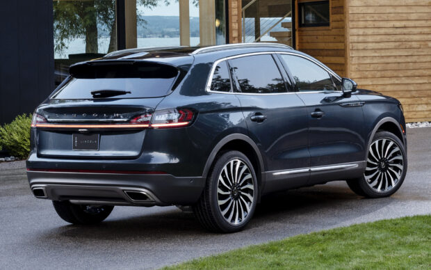 A sleek black Lincoln Nautilus is parked outside a modern home near greenery and water, HD Desktop Wallpaper