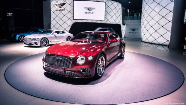 A red Bentley Continental GT is showcased indoors with other models present, 4K Desktop Wallpaper