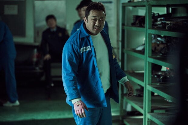 Ma Dong Seok stands in a dimly lit prison room with blue uniform and pink gloves, HD Desktop Wallpaper