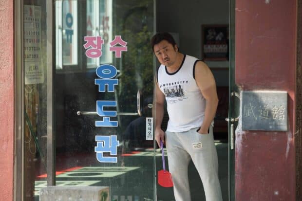 Ma Dong Seok is standing outside a martial arts studio holding a fly swatter in his hand, HD Desktop Wallpaper