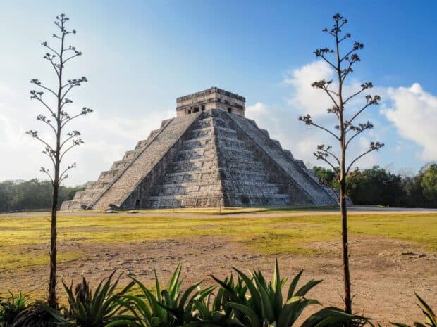 The majestic Chichen Itza pyramid stands tall surrounded by plants under a bright blue sky, HD Desktop Wallpaper