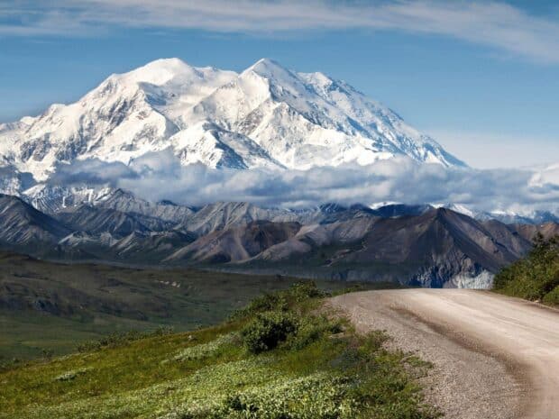 The snow capped Denali National Park And Preserve rises above green valleys and a winding dirt road, HD Desktop Wallpaper
