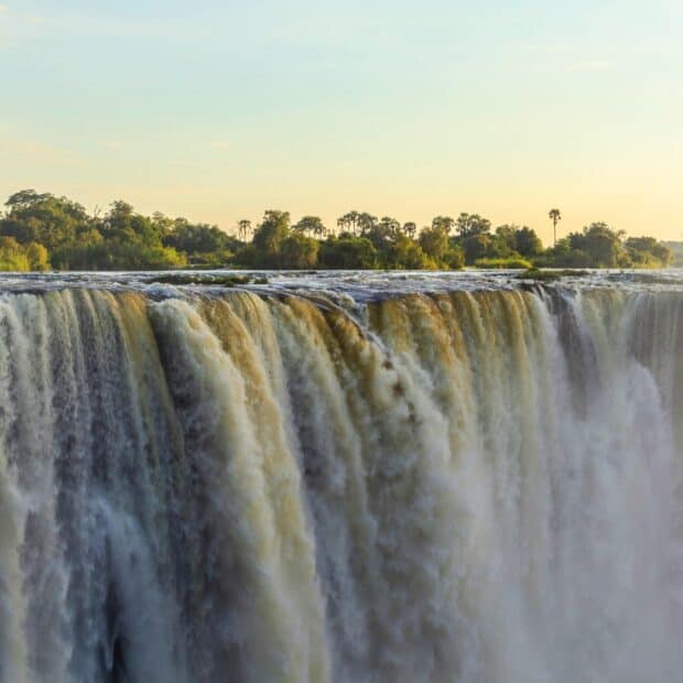 A breathtaking waterfall at Devils Pool Zambia with lush greenery in the background, HD Desktop Wallpaper