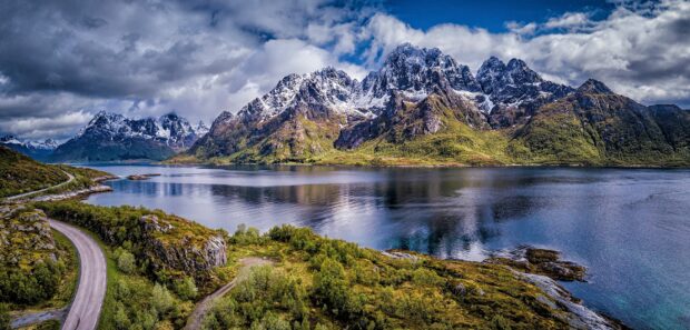 A panoramic view of Norwegian fjords with snow capped mountains and reflective water, 2K Desktop Wallpaper