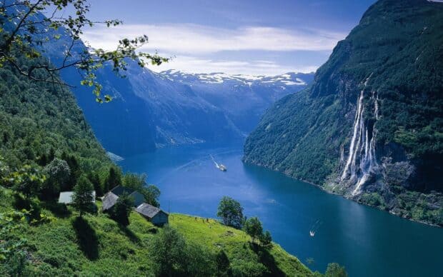 A serene view of Norwegian fjords with waterfalls and boats on the water, 2K Desktop Wallpaper