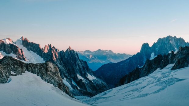 A vast glacier surrounded by rugged mountains under a clear sky, 4K Desktop Wallpaper