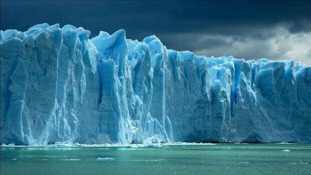 A massive glacier rises above the icy waters under a stormy sky in glacier wallpapers 4K and HD, HD Desktop Wallpaper