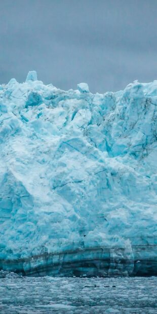 A massive glacier with vibrant blue ice and floating ice chunks in cold water, HD Phone Wallpaper