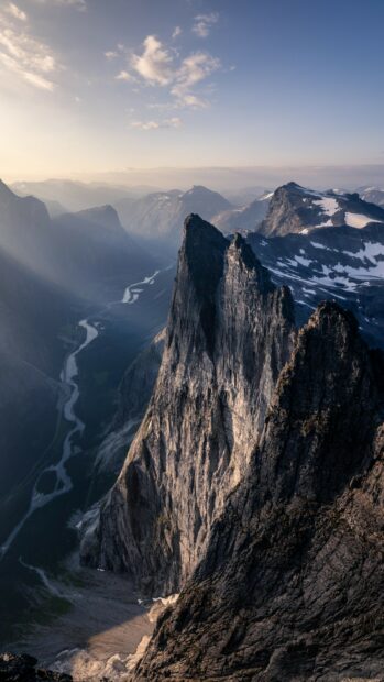 A scenic view of Norway with towering rocky mountains and winding river under a cloudy sky, 4K Phone Wallpaper