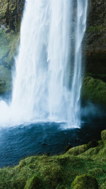 A waterfall cascades over rocky cliffs into a blue pool surrounded by greenery in Uganda Wallpapers, 4K Phone Wallpaper