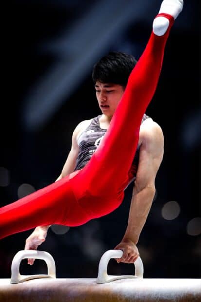 A male gymnast is shown executing a move on the pommel horse with red pants, HD Mobile Wallpaper