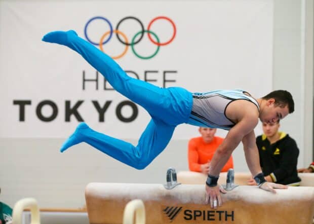 A male gymnast is executing a skill on the pommel horse during a gymnastics competition in Tokyo, 2K Desktop Wallpaper