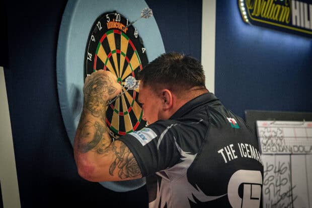 A man with tattoos aiming darts at a dartboard during a game of darts, 2K Desktop Wallpaper
