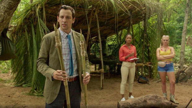 A man holds wooden stakes while two women stand near a makeshift shelter in a tropical area, HD Desktop Wallpaper