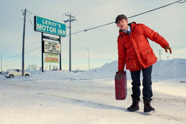 A man in a red jacket holding a gas can near Leroy's Motor Inn in winter snow, HD Desktop Wallpaper
