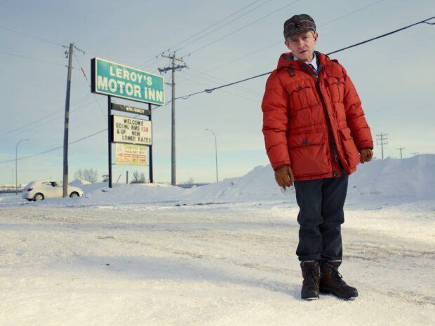 A man wearing a red jacket and gloves stands on snow near a motel sign in a winter setting with Fargo Wallpapers, HD Desktop Wallpaper