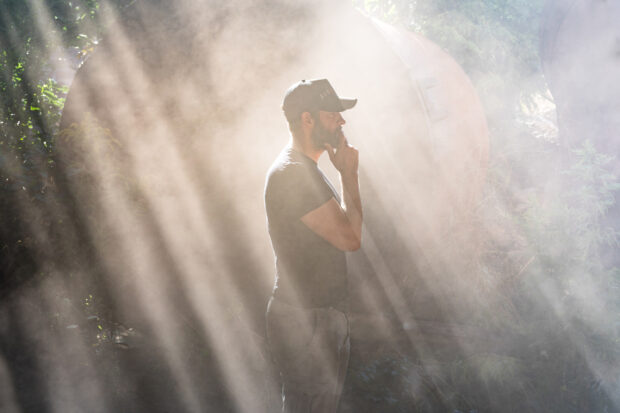 A man in a cap standing thoughtfully in misty forest light rays, 2K Desktop Wallpaper