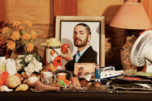 A portrait of Marc Jacobs holding an orange fruit surrounded by various vintage items, HD Desktop Wallpaper