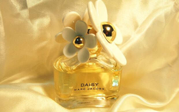 A Marc Jacobs perfume bottle with white daisy decorations on a golden fabric background, HD Desktop Wallpaper