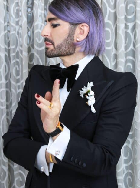A man with purple hair and a beard poses wearing a black tuxedo and bow tie representing Marc Jacobs, 2K Desktop Wallpaper