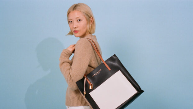 A woman carries a Marc Jacobs tote bag in a beige sweater against a blue backdrop, HD Desktop Wallpaper