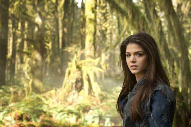 Marie Avgeropoulos stands in a mossy forest wearing a blue jacket, 2K Desktop Wallpaper
