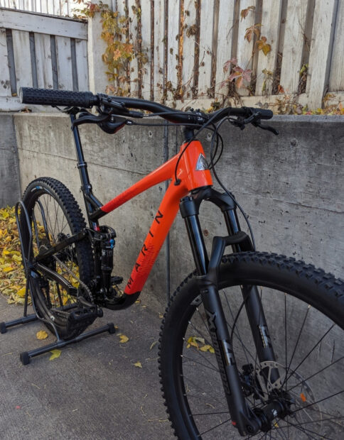 A Marin Bikes model leaning on a stand near a concrete wall with autumn leaves, HD Mobile Wallpaper