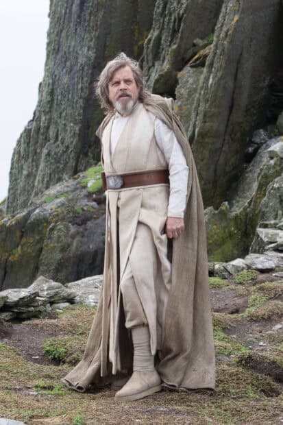 Mark Hamill stands in Jedi costume near rocky cliffs, HD Desktop Wallpaper