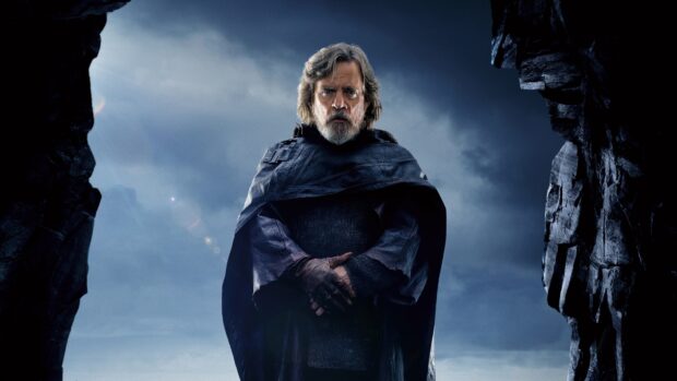 Mark Hamill stands solemnly wearing a dark cloak with rocky cliffs behind him, 4K Desktop Wallpaper