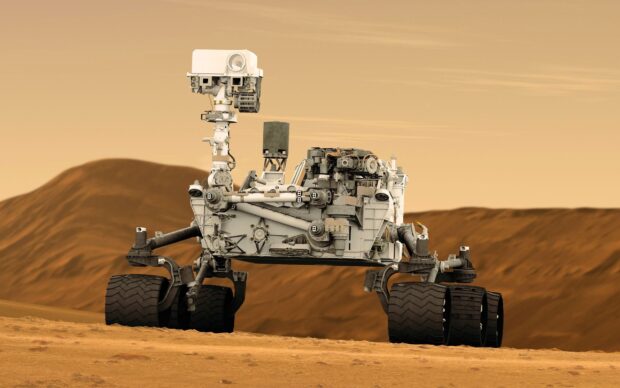 The Mars Curiosity Rover is shown driving across the rocky surface of Mars, 2K Desktop Wallpaper
