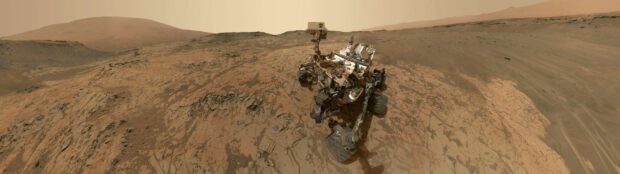 The Mars Curiosity Rover is captured on the rocky surface of Mars with hills in the background, 4K Desktop Wallpaper