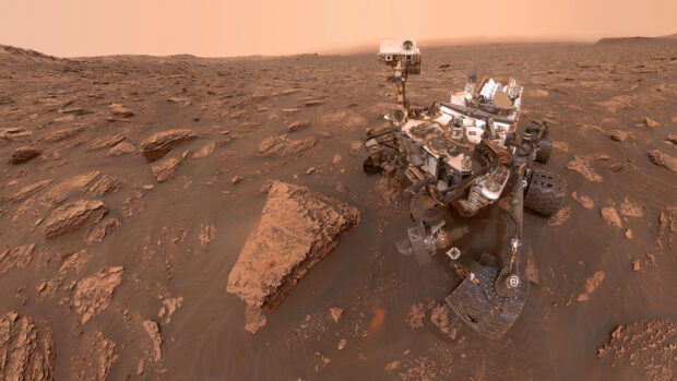 The Mars Curiosity Rover explores rocky terrain under a dusty orange sky, 2K Desktop Wallpaper