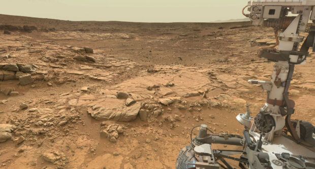 The Mars Curiosity Rover is shown navigating the rocky surface of Mars under a pale sky, HD Desktop Wallpaper