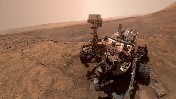 The Mars Curiosity Rover explores rocky terrain under reddish skies on Mars, HD Desktop Wallpaper
