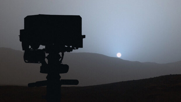 The Mars Curiosity Rover silhouette is visible against the setting sun on the Martian horizon, 4K Desktop Wallpaper