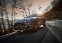A blue Maserati Levante is driving through a forested area during sunset, 2K Desktop Wallpaper