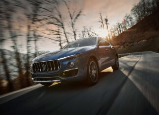A blue Maserati Levante is driving through a forested area during sunset, 2K Desktop Wallpaper