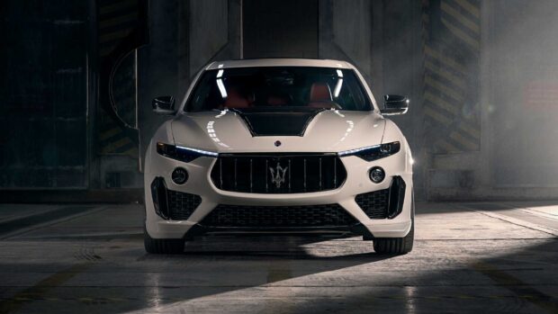 A white Maserati Levante is parked in a dimly lit industrial setting showing its front design, HD Desktop Wallpaper