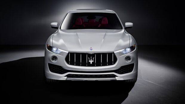 The white Maserati Levante is captured in a studio with its headlights on and a detailed front grille visible, 4K Desktop Wallpaper