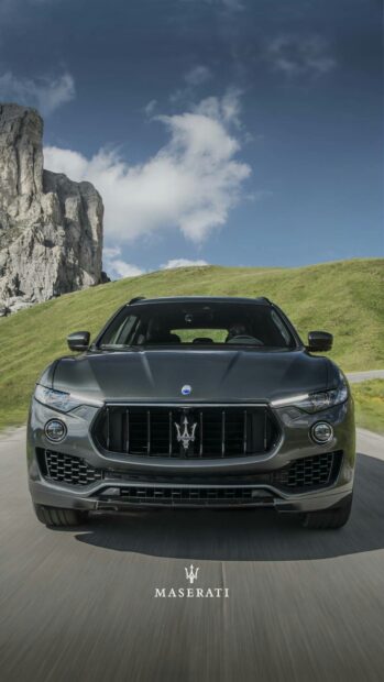 A Maserati Levante drives along a mountain road with rocky cliffs and green hills in the background, HD Phone Wallpaper