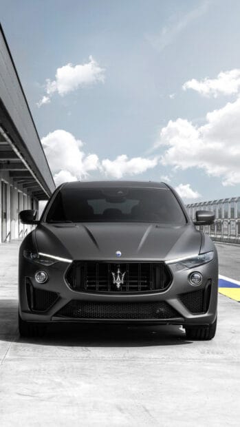 A matte black Maserati Levante is parked on a racetrack with a cloudy sky in the background, HD Phone Wallpaper