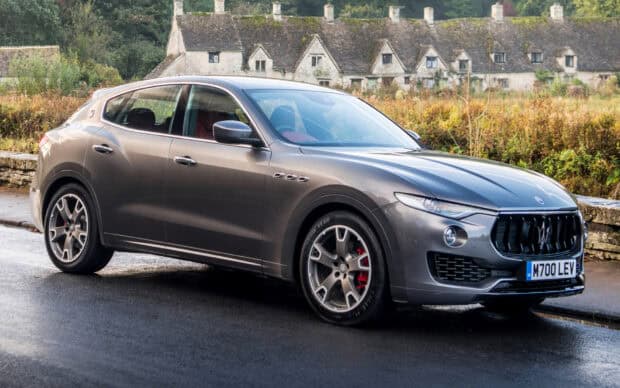 A Maserati Levante is parked on a wet road near countryside stone cottages, HD Desktop Wallpaper