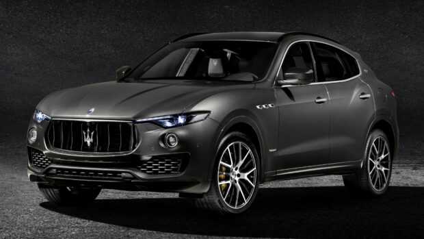 A sleek black Maserati Levante stands with headlights on against a dark textured background, HD Desktop Wallpaper