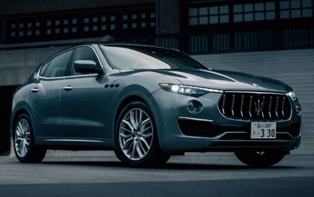 A gray Maserati Levante is parked in front of a modern building at dusk, HD Desktop Wallpaper